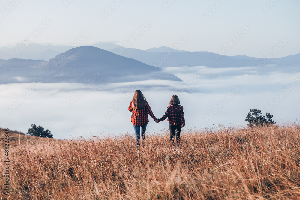 Two Girls in Red Plaid Shirts Walking in the Mountains