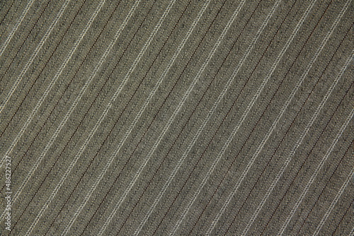 The texture of the costume fabric, diagonal pattern, neutral color. diagonal fabric background, material. Striped texture. Coarse woolen fabric with a black-white-brown pinstripe print.