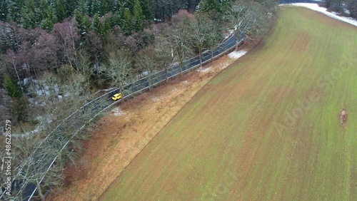 Slow-moving car driving on a road in the middle of a farm land - aerial drone view photo