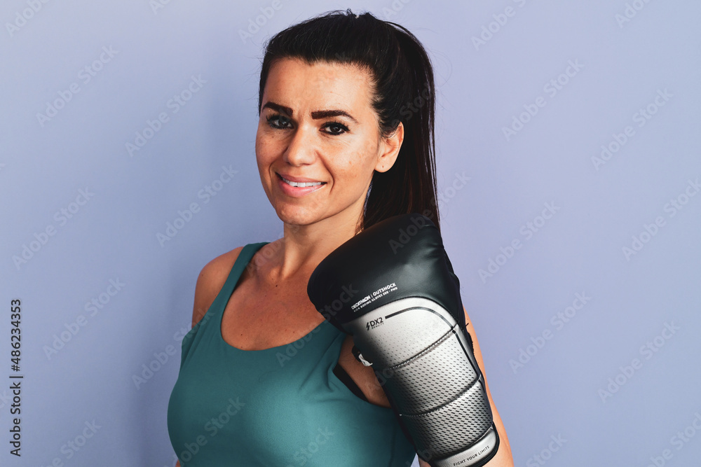 Naklejka premium Portrait of Smiling young Beautiful sports woman posing putting hands together in Boxing Gloves isolated on grey background