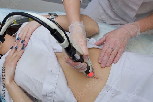 Laser procedure on the abdomen. The hand holds the laser machine on the abdomen