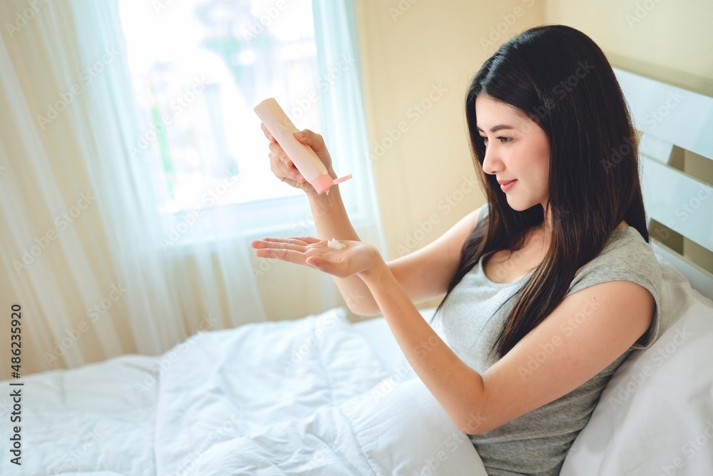 asian woman use lotion hands cream moisture and white moisturize lotion on bed in bedroom, therapy beauty, skin care concept. asian woman use lotion hands cream moisture and white moisturize lotion on bed in bedroom, therapy beauty, skin care concept.