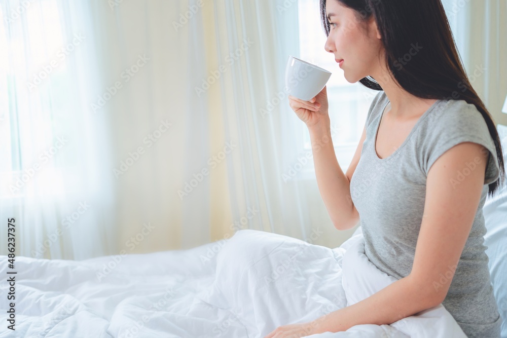 Asian woman drinking coffee in the morning in bed. Asian woman drinking coffee in the morning in bed.