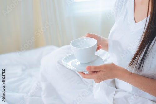 Asian woman drinking coffee in the morning in bed.