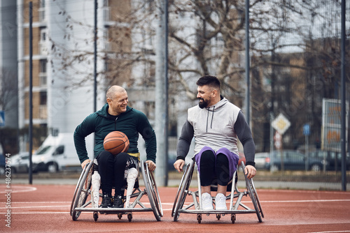Fotografi Happy basketball players in wheelchairs on an outdoor sports court