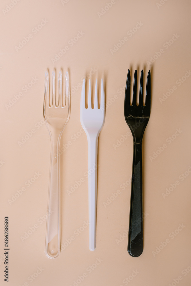 Disposable plastic cutlery on peach background Disposable plastic cutlery on peach background