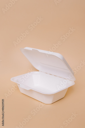 Disposable plastic containers for food on a peach background. Concept of using eco utensils.
