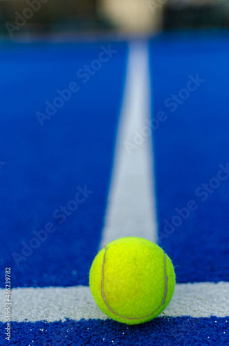 selective focus of a ball on the white line of a blue paddle tennis court © Vic