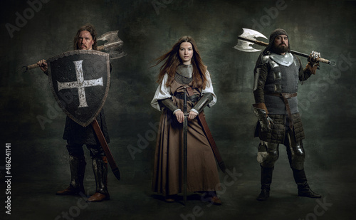 Creative art collage with brutal serious medieval warriors or knights with wounded faces holding shield, sword isolated over dark vintage background.