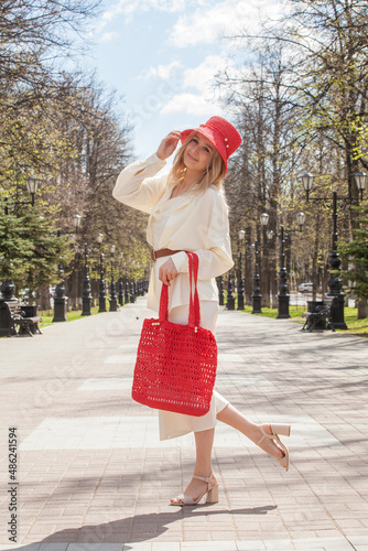Beautiful blonde on a walk with a bag and a handmade red hat