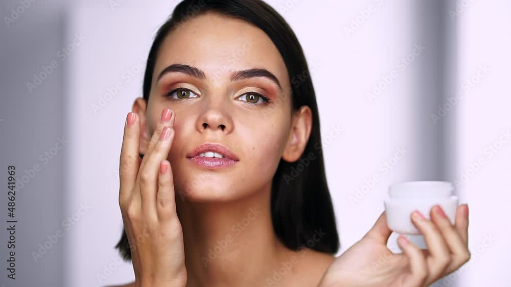 Portrait of woman applying moisturizer cream on her face. Youth and Skin Care Concept. Close up Portrait of woman applying moisturizer cream on her face. Youth and Skin Care Concept. Close up
