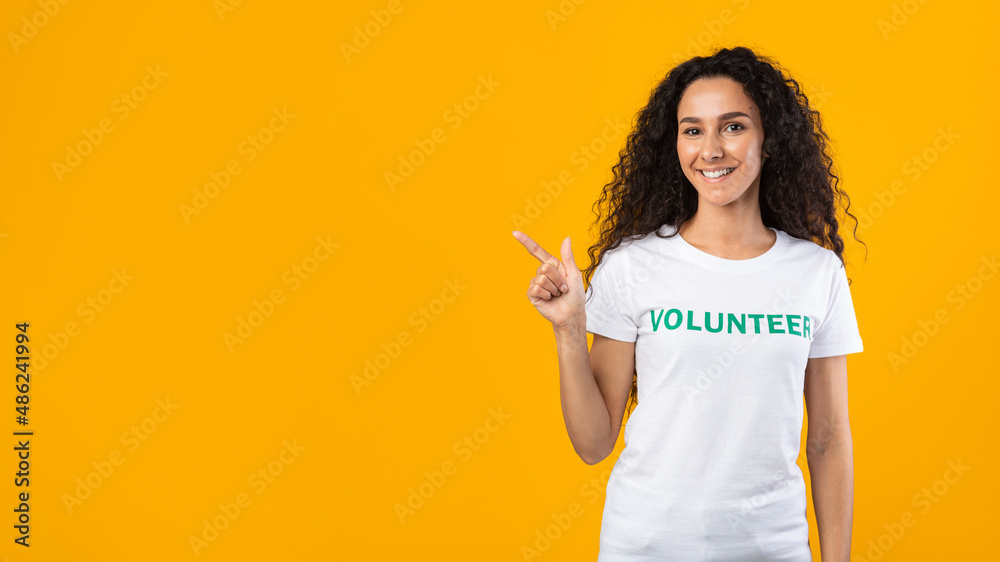 Volunteer Lady Pointing Finger At Free Space, Yellow Background, Panorama Volunteer Lady Pointing Finger At Free Space, Yellow Background, Panorama