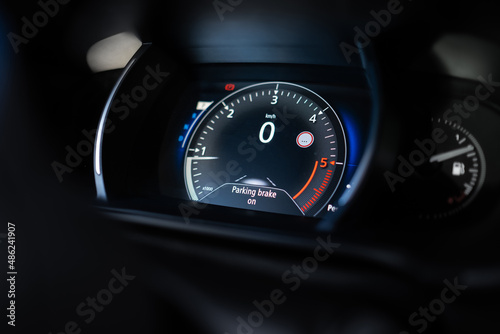 Modern car dashboard shows parking brake on message. Zero kilometre