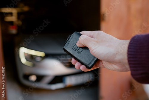 Close-up of a man's hand locking or unlocking a car with keyless in garage. Black leather case for keyless photo