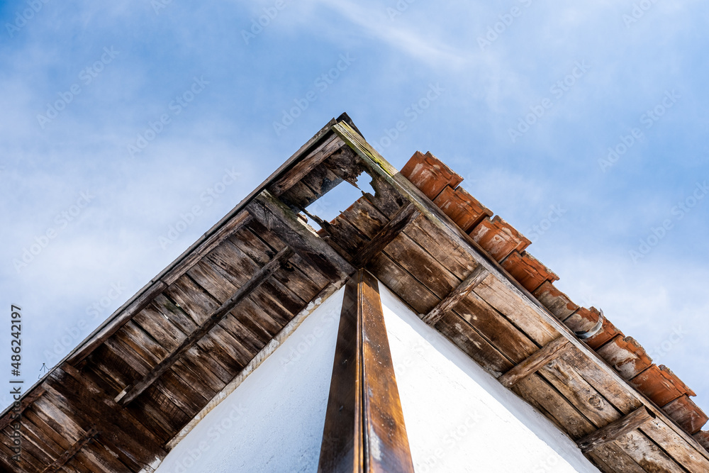 Damaged roof of a house. Broken roof board. Damaged wooden roof. Hole