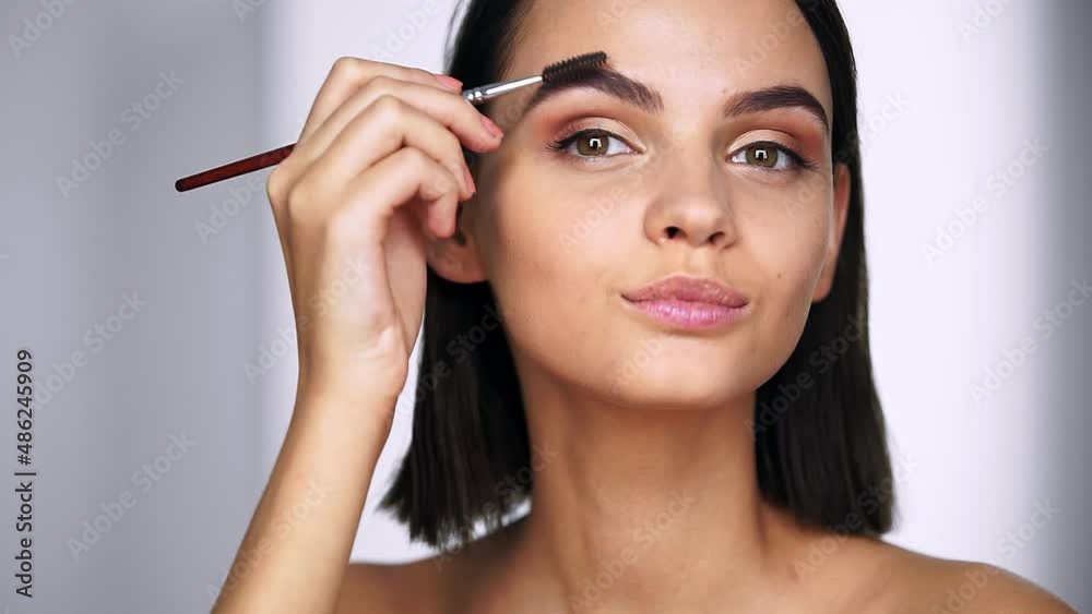 Beautiful woman using brush for eyebrows and applies wax, does correction of eyebrows. Beauty and Skin care concept Beautiful woman using brush for eyebrows and applies wax, does correction of eyebrows. Beauty and Skin care concept