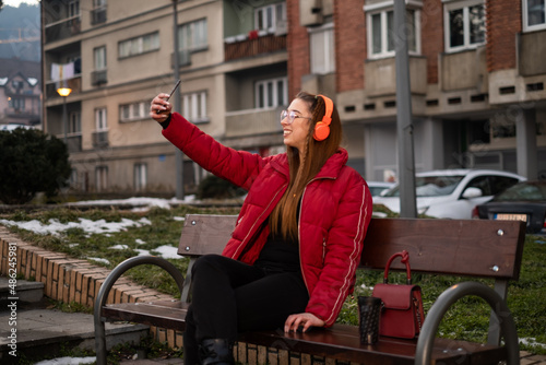 young girl on a bench takes a photo of herself © Jovan