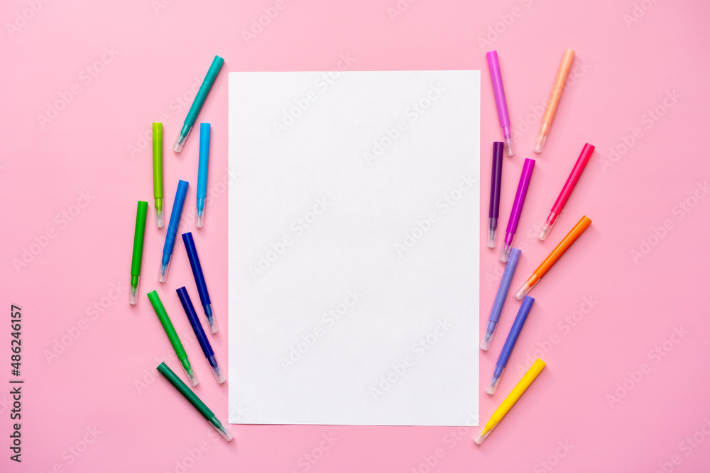 multi-colored felt-tip pens on a pink background, space for text, top view, blank sheet multi-colored felt-tip pens on a pink background, space for text, top view, blank sheet