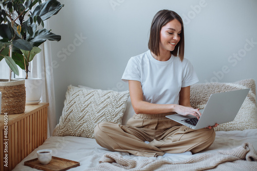 Young woman working on laptop at home in bed