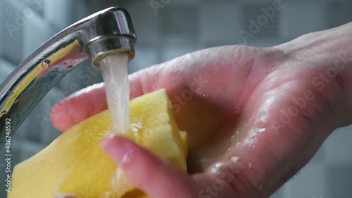 Man's hand with a sponge for washing dishes soaked in detergent and a lot of foam