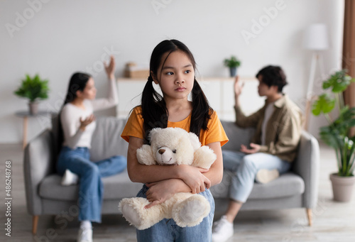Fotografia Lonely sad chinese teen girl with toy suffers from scandal of parents, young asi