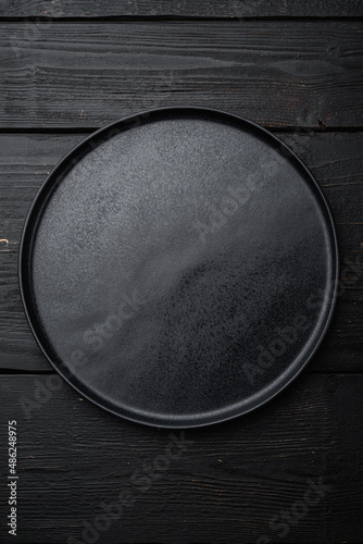 Black plate, on black wooden table background