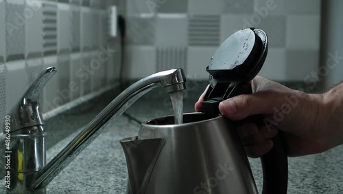 open the faucet to fill the electric kettle in the kitchen. closing the electric kettle and turning it on to heat water