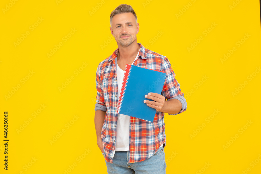 Happy teacher man holding school books for education yellow background, copy space Happy teacher man holding school books for education yellow background, copy space