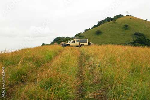 A safari vehicle in the savannah grassland landscapes of Chyulu Hills National Park, Kenya