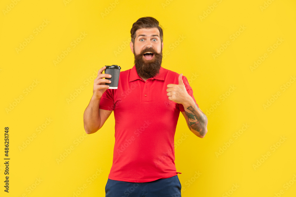 Surprised man in casual red tshirt giving thumb holding disposable cup, paper-cup coffee Surprised man in casual red tshirt giving thumb holding disposable cup, paper-cup coffee