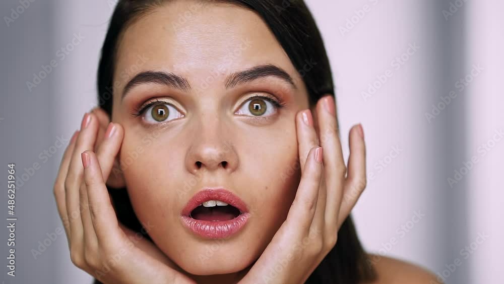 Upset girl looks in the mirror on her face, checks the appearance of wrinkles. Beauty and Skin care concept. Close up Upset girl looks in the mirror on her face, checks the appearance of wrinkles. Beauty and Skin care concept. Close up