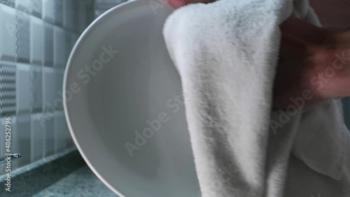 a man wipes wet dishes in the kitchen with a white towel with his hands. closeup shot