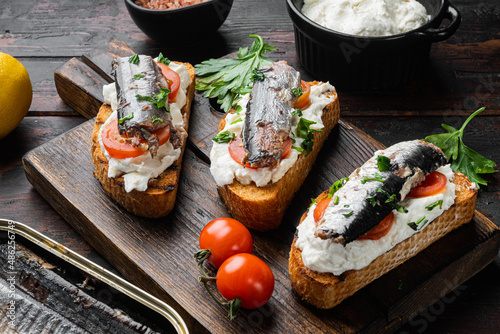 Ricotta sardine toast, on old dark wooden table background