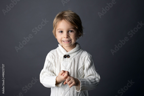 Cute little toddler boy, showing FRIEND gesture in sign language on gray background, isolated image, child showing hand sings