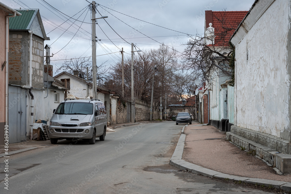 View of a small street in the old town. Cars are parked near sidewalks and houses. Sevastopol, Republic of Crimea.