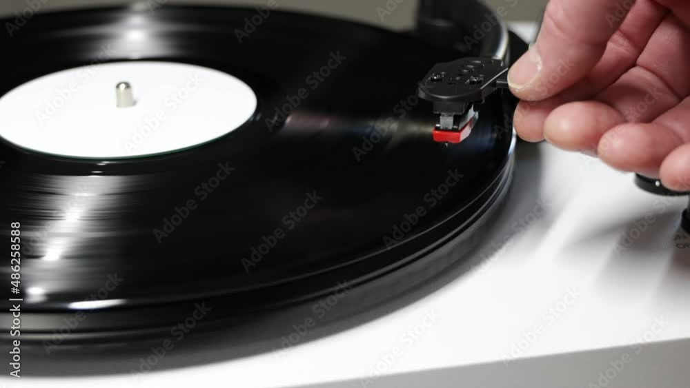 Hand turns on a vintage vinyl record. Vinyl turntable with vinyl plate. Gramophone record player. Retro sound technology to play music