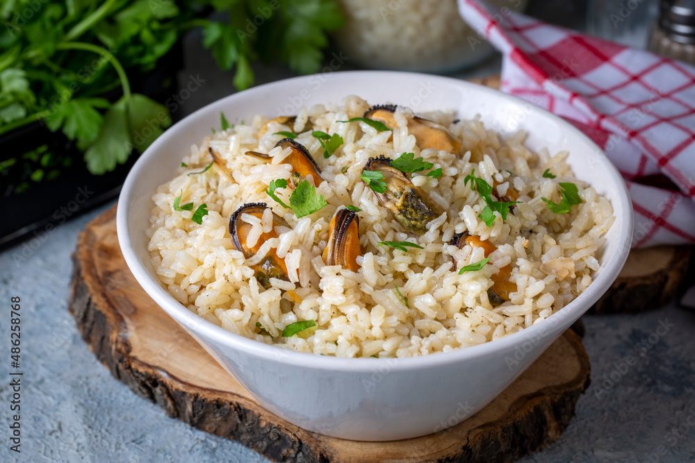 Mussel rice pilaf. Rice with mussels on small white plate on ceramic. Mussel rice pilaf. Rice with mussels on small white plate on ceramic.