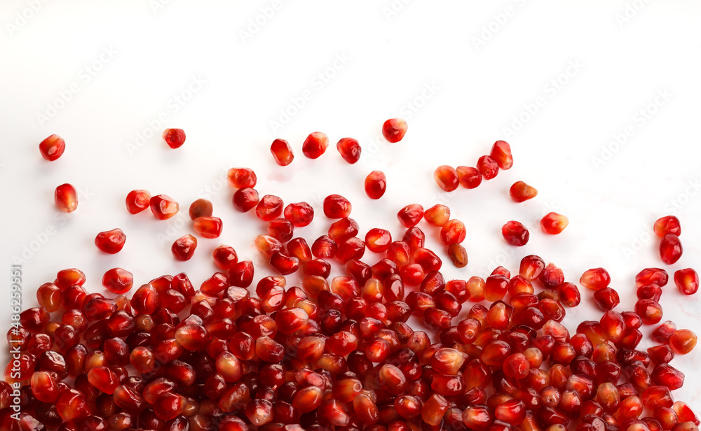 Close-up red pomegranate seeds on white background. Fresh juicy pomegranate seeds isolated on white., top view, selective focus, copy space Close-up red pomegranate seeds on white background. Fresh juicy pomegranate seeds isolated on white., top view, selective focus, copy space