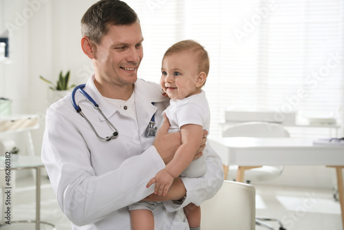 Pediatrician with cute little baby in clinic. Space for text