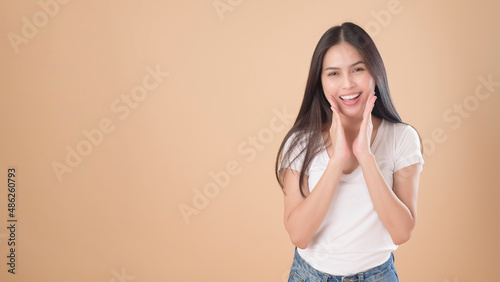 A Portrait of Asian woman with white T-shirt over Light brown background studio
