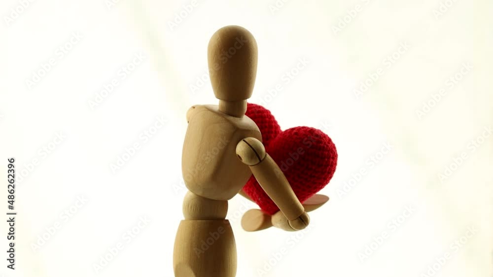 a wooden man is spinning with a heart in his hands. love concept a wooden man is spinning with a heart in his hands. love concept