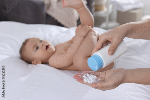 Mother with dusting powder near her baby at home, closeup