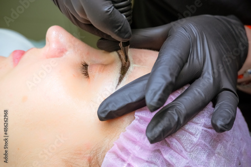 Cosmetologist applying permanent makeup on eyebrows Selective focus and shallow Depth of field.Mikrobleyding eyebrows workflow in a beauty salon