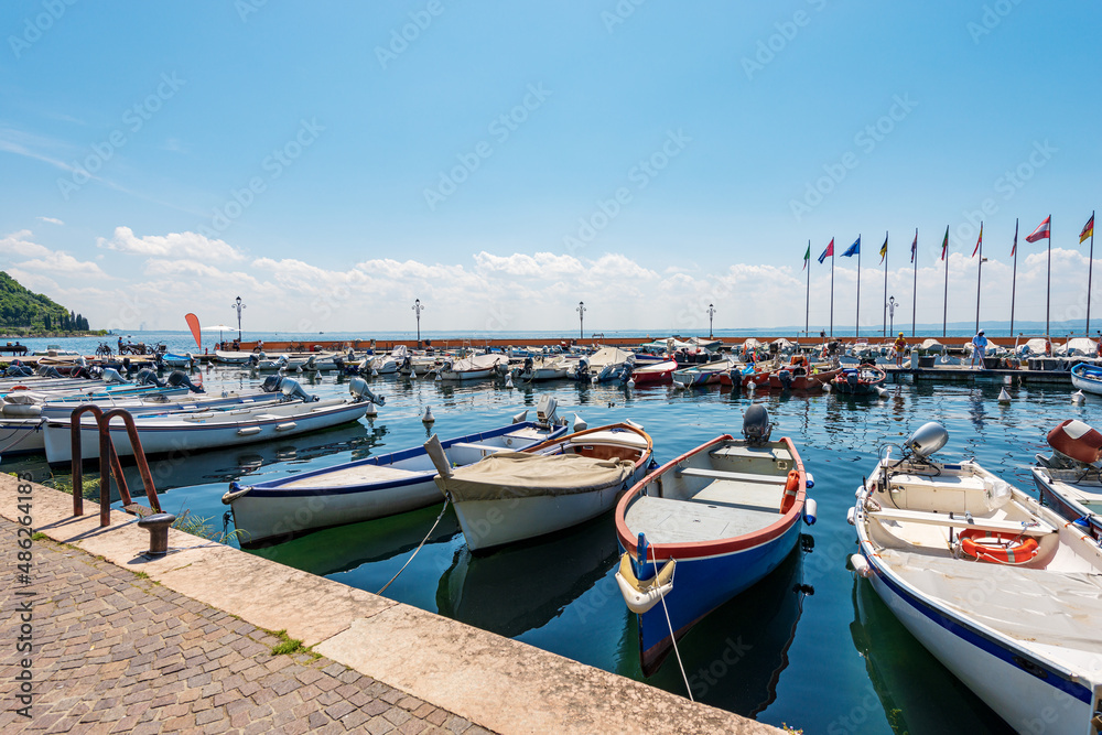 Small port of Lake Garda (Lago di Garda) with many boats moored, in front of Garda town, famous tourist resort in Verona province, Veneto, Italy, southern Europe.