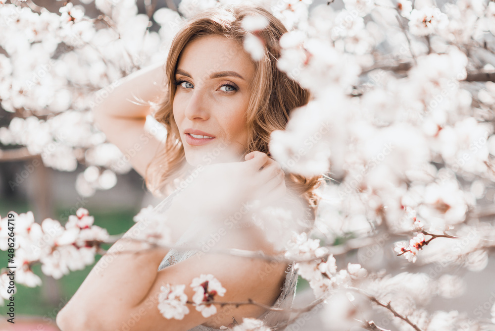 Portrait of pretty blonde girl posing against the spring blooming trees in the garden. Portrait of pretty blonde girl posing against the spring blooming trees in the garden.