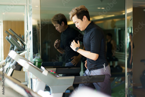 Active Asian sportsman making a cardio exercise by running on the treadmill.