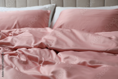 Bed with beautiful pink silk linens, closeup