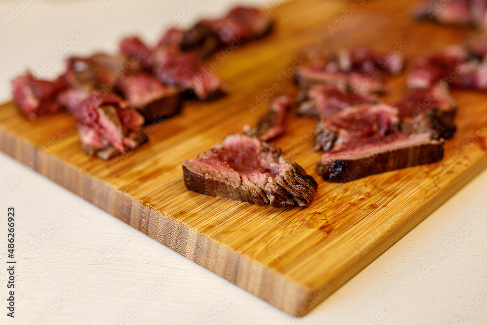 sliced beef pieces on a wooden tray.