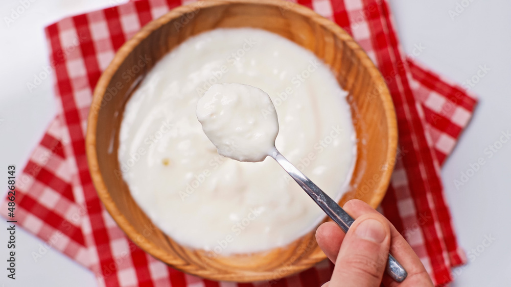 top view of man holding spoon with yogurt near blurred bowl on plaid cloth napkin isolated on white top view of man holding spoon with yogurt near blurred bowl on plaid cloth napkin isolated on white