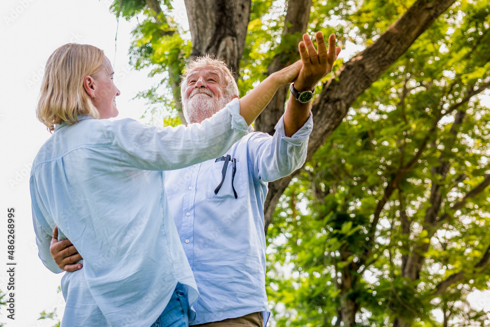 elderly man and woman caucasian middle age couple holding hands dancing in park, old senior couple health care active family having fun. elderly man and woman caucasian middle age couple holding hands dancing in park, old senior couple health care active family having fun.